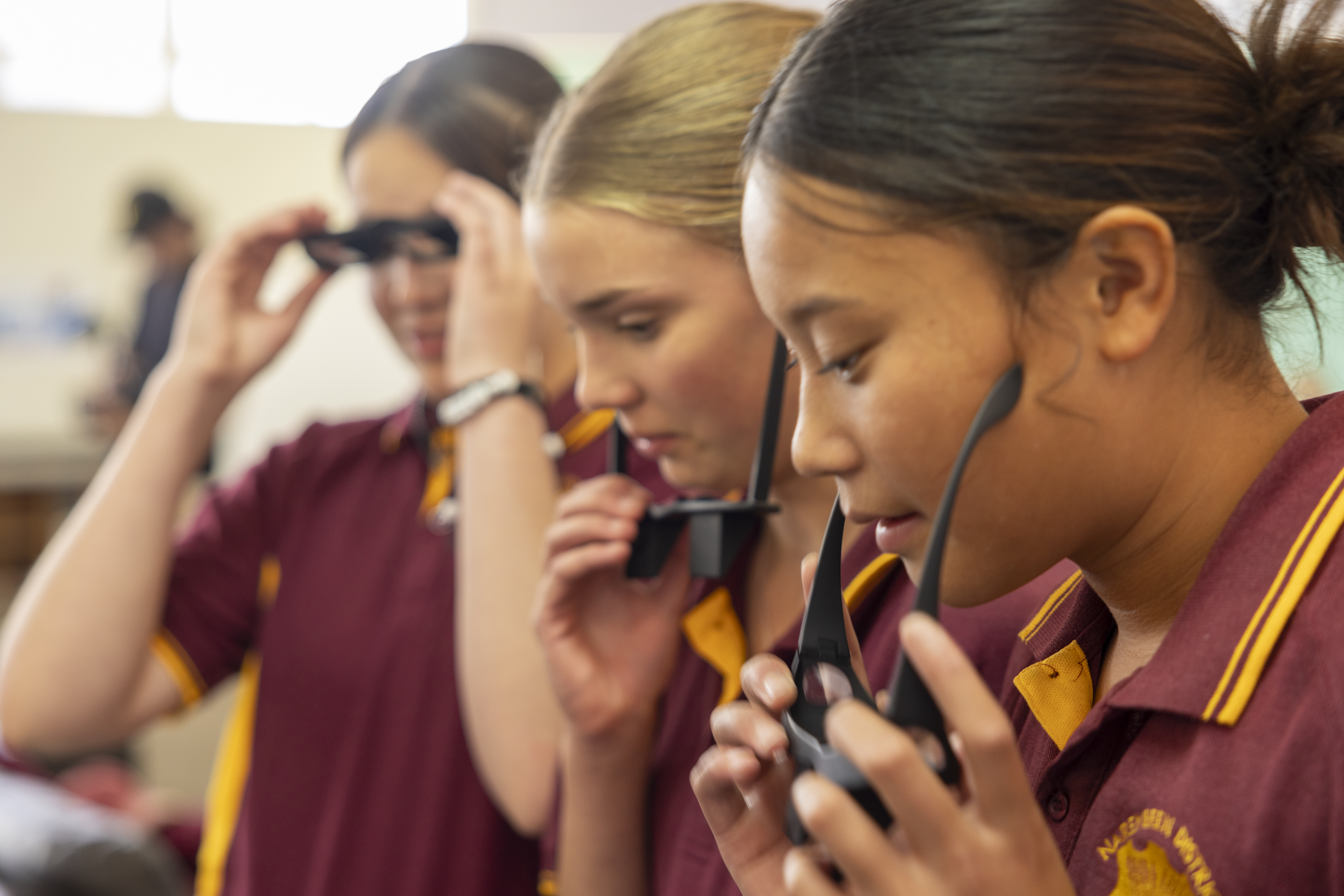Three students putting on 90-degree glasses