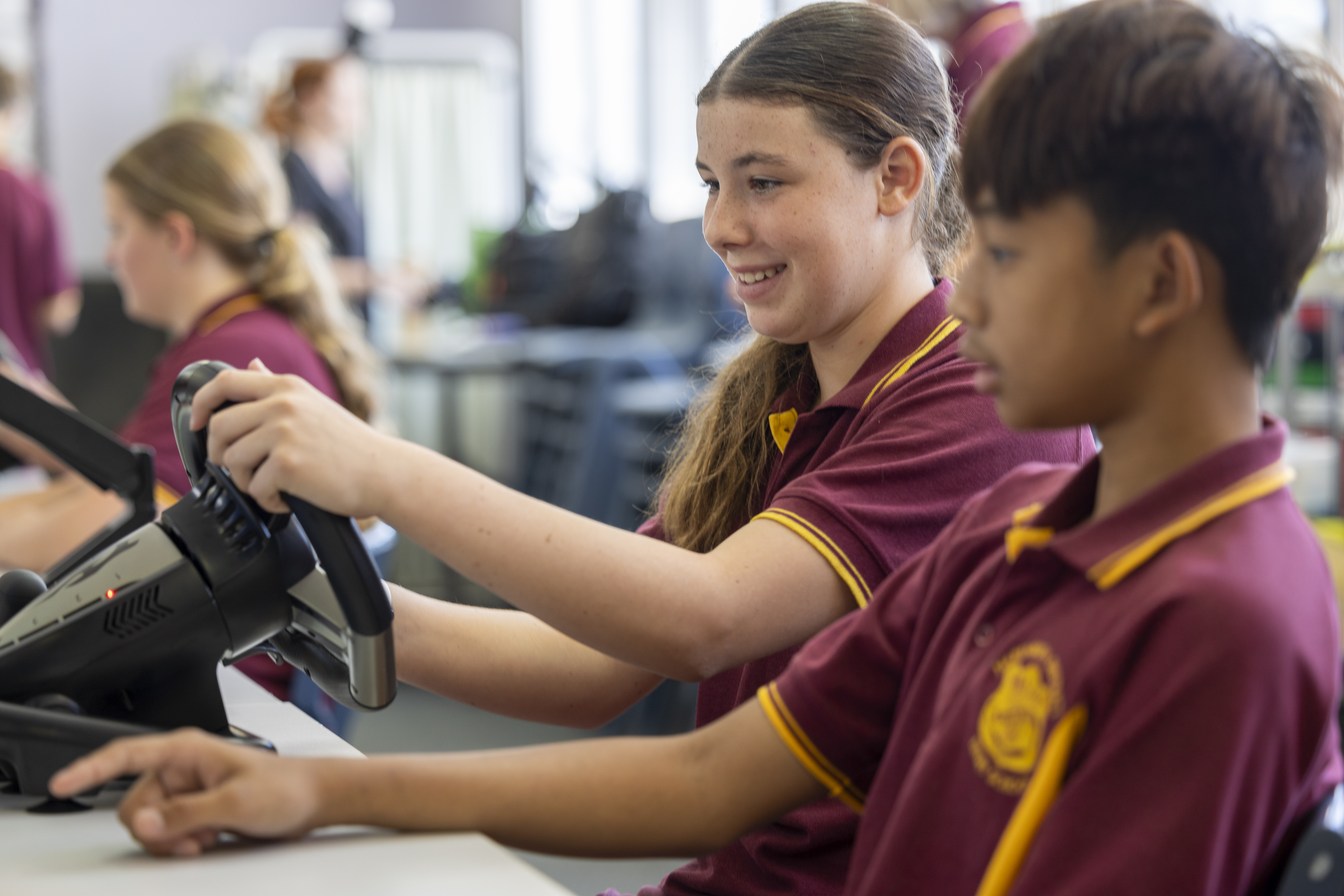 Two students using steering wheel and interacting with the screen. 